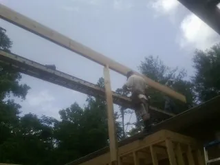 Carpenter setting a ridge beam over a new addition frame — Ice Dam Removal by Roofing Brothers in Port Gibson