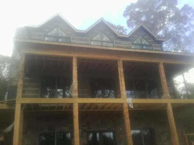 Dormers and porch framing on a large log home under construction — Roof Coating work by our crew in Port Gibson