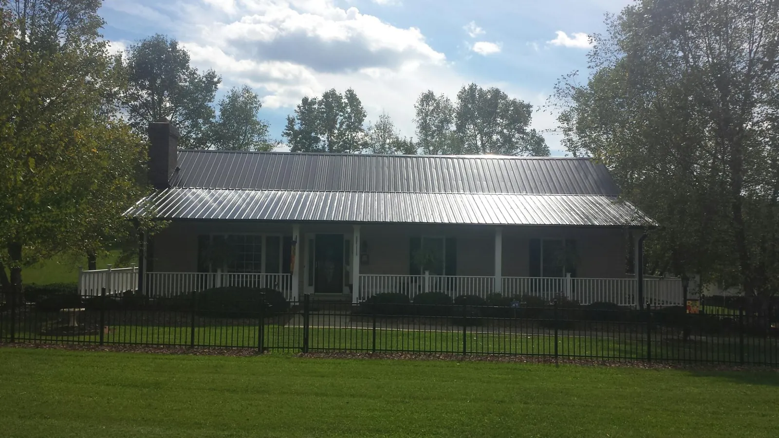 Gray metal roof on a brick ranch with a full width front porch — Gutter Guard Installation work by our crew in Port Gibson