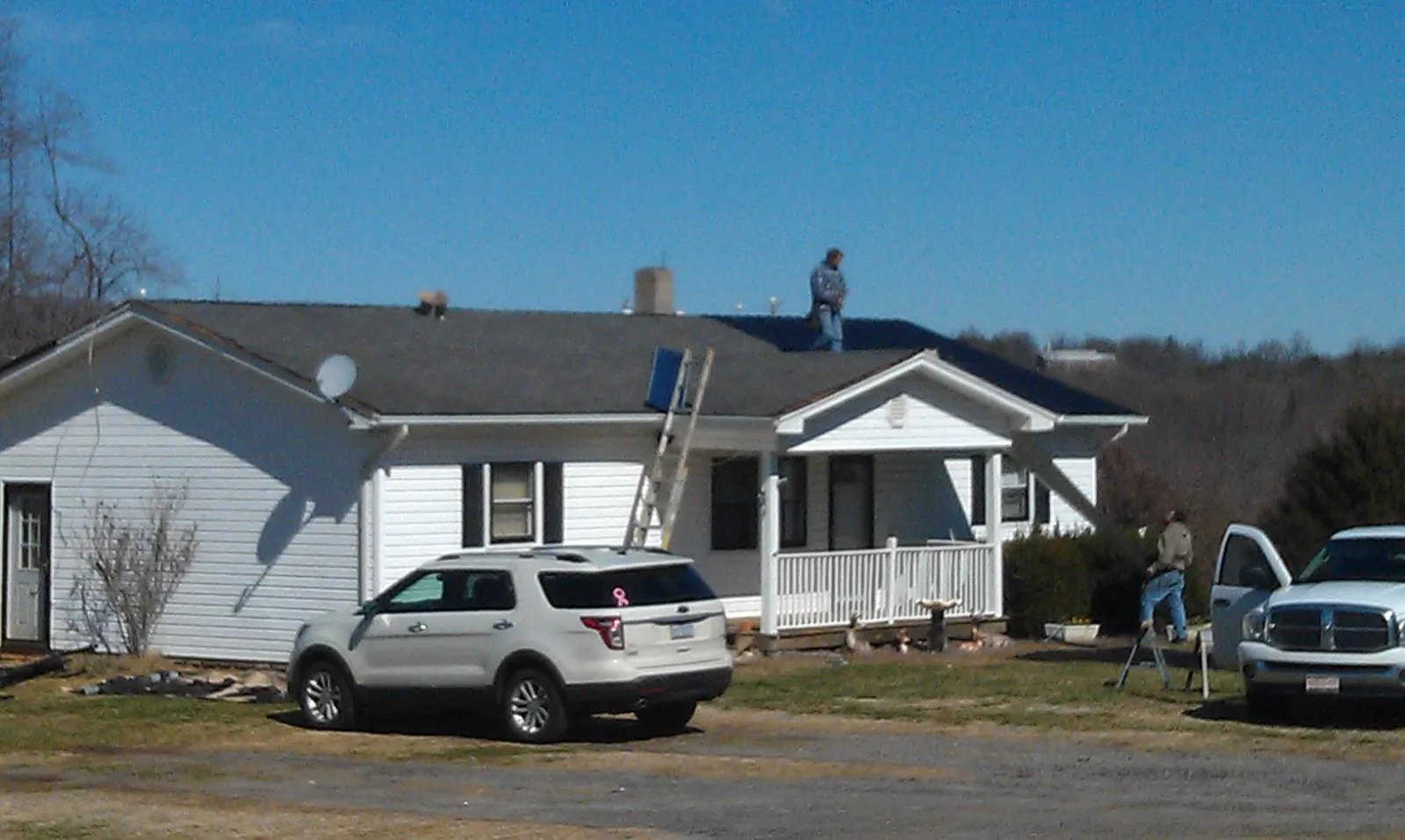 Roofers stripping shingles from a white ranch house roof in Port Gibson
