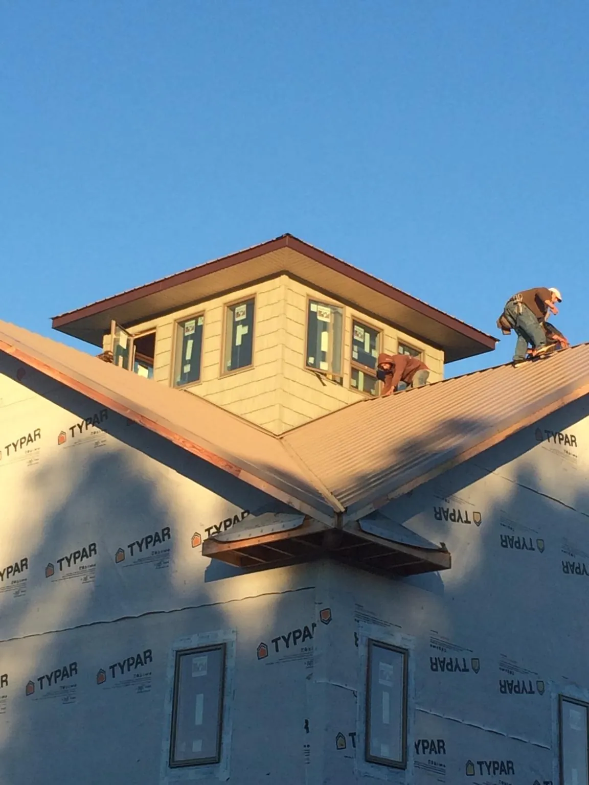 Roofers working around a rooftop cupola on a new metal roof at sunset — Roof Waterproofing in Port Gibson by Roofing Brothers